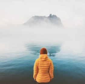 Iemand op een berg kijkt uit over de wolken